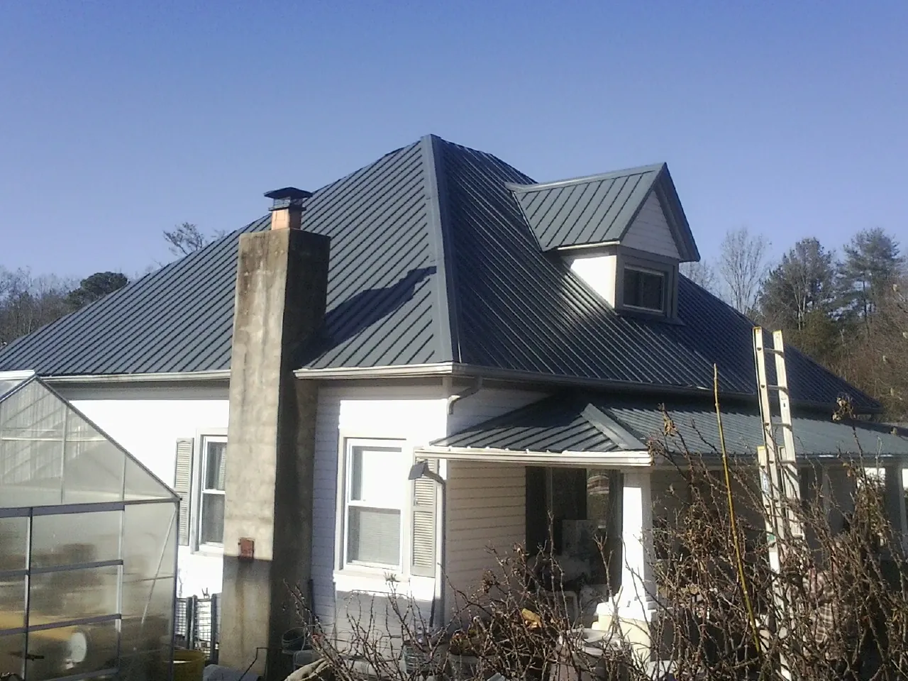 Dark blue standing seam metal roof on a white farmhouse with dormer — Slate & Tile Roof Repair by Roofing Brothers in Harford