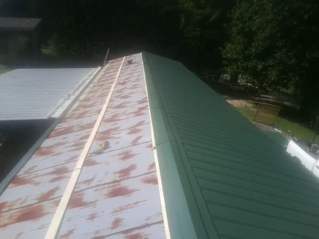 Old rusted panels beside newly installed green metal roofing — Wind Damage Roof Repair by Roofing Brothers in Harford