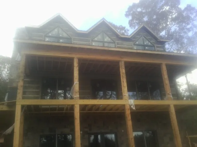 Dormers and porch framing on a large log home under construction — Roof Coating work by our crew in Harford