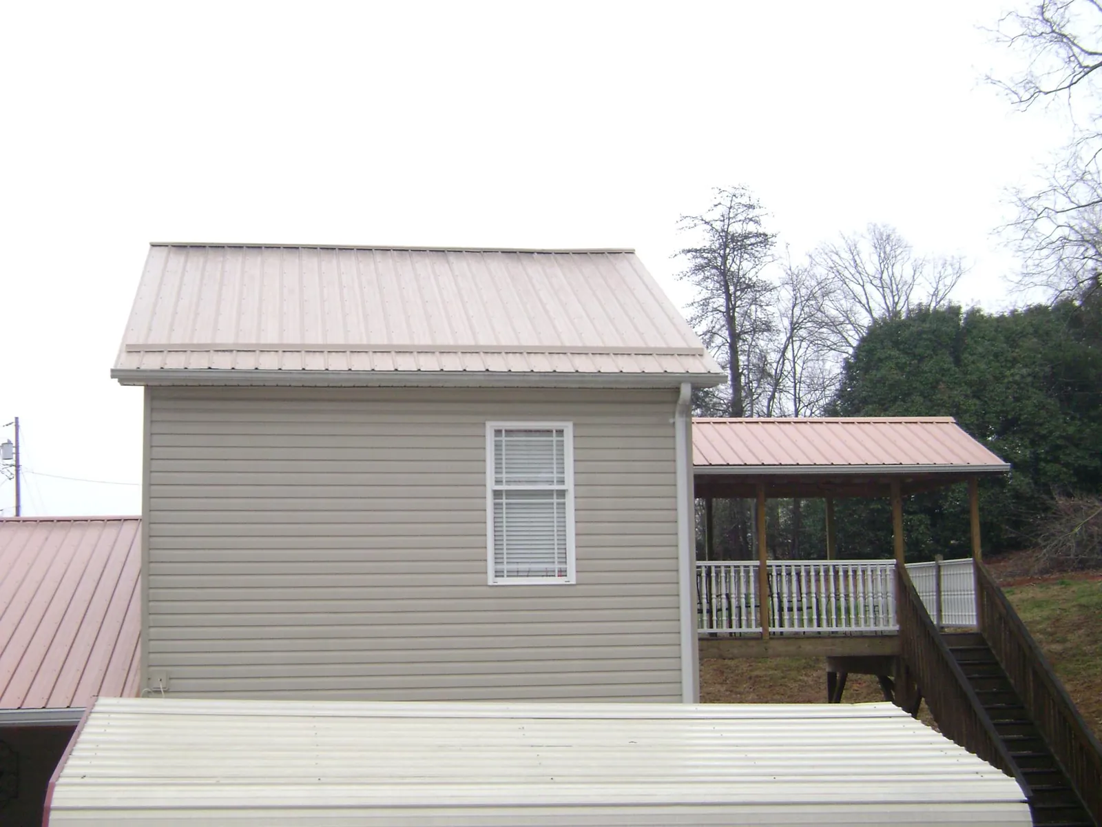 Tan metal roofs on a two story addition and attached porch, from a Roof Replacement job in Harford