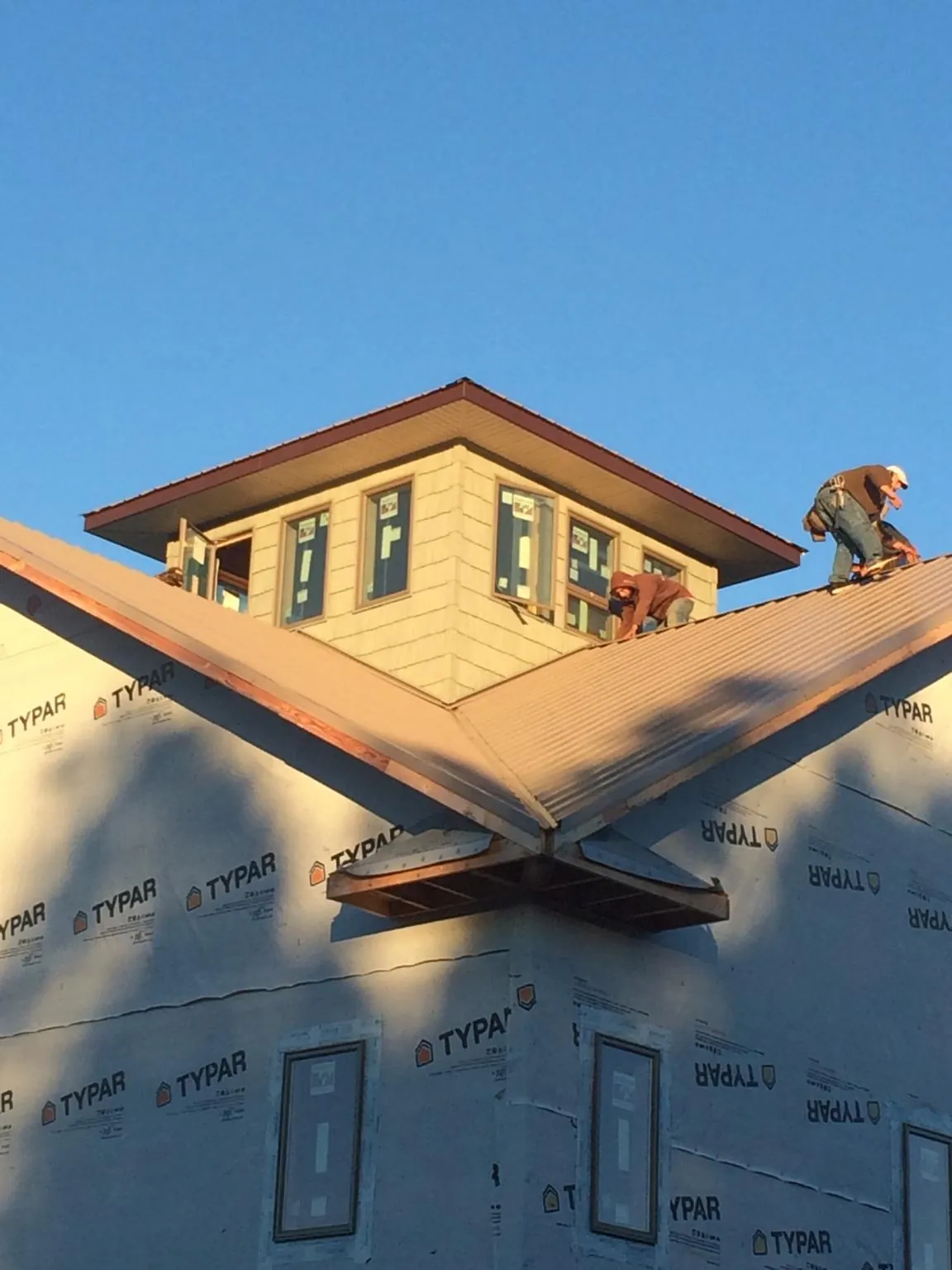 Roofers working around a rooftop cupola on a new metal roof at sunset — Roof Waterproofing in Harford by Roofing Brothers